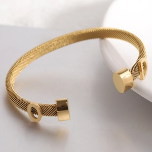 Close-up of gold 6mm stainless steel cable wire cuff with OD letter charms on white ceramic