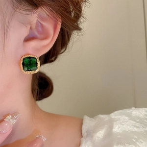 Macro view of square emerald zircon earring with gold plated border on model