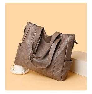 Detail view of large taupe tote bag with vintage faux leather texture and side pockets