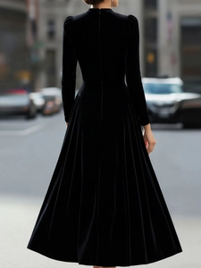 Back view of elegant long sleeve black velvet maxi dress showing fabric drape and texture