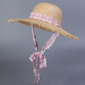 Close-up of woven raffia sun hat with pink gingham ribbon tie and frayed brim edge
