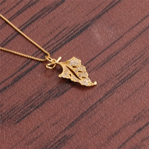 Detailed view of a gold leaf pendant with clear cubic zirconia stones on a box chain