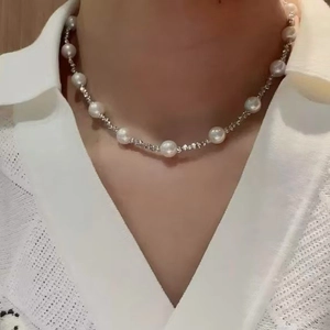 Elegant white round pearl necklace with silver spacers on woman wearing white shirt