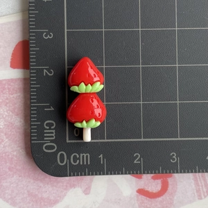 Detailed view of resin strawberry charms on a measuring mat showing 2.5cm size