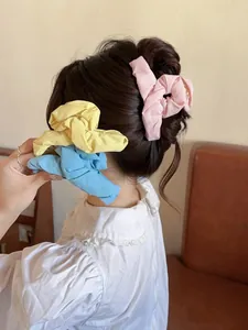 Detailed view of pink, yellow, and blue pleated fabric hair claws on a dark hairstyle