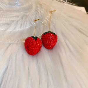 Vue macro détaillée de boucles d'oreilles fraises en strass rouges et crochets dorés
