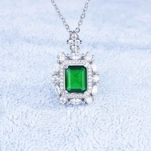 Macro shot of emerald-cut green stone pendant with zircon halo on silver chain