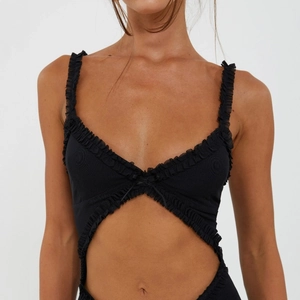 Dettaglio di un body nero a coste con scollo a V a balze e taglio in vita alla moda