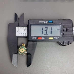 Digital caliper measuring the 13.1mm diameter of a gold evil eye pendant with zircon