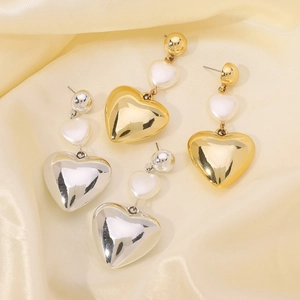 Detail of heart-shaped drop earrings with faux pearls in gold and silver finishes