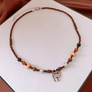 Vintage brown beaded necklace with iridescent cat pendant on brown silk fabric