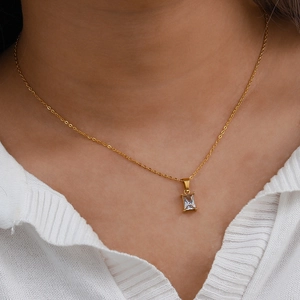 Détail d'un collier doré avec pendentif rectangulaire en zircon porté par un mannequin