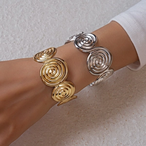 Detail of gold and silver spiral metal cuff bracelets worn on a woman's wrist