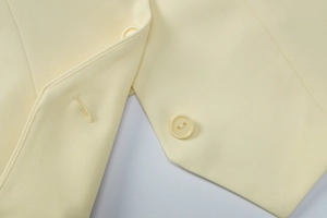 Detail view of double-hole buttons and fine stitching on the pale yellow blazer jacket