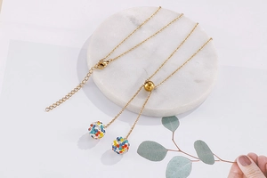 Detailed shot of golden necklace featuring crystal-encrusted spheres on white marble