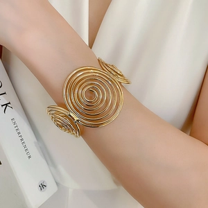 Close-up of golden spiral wave bracelet on model wrist with elegant minimalist background