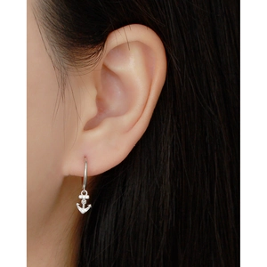 Detail shot of a silver sterling anchor hoop earring with sparkling zircon on a model
