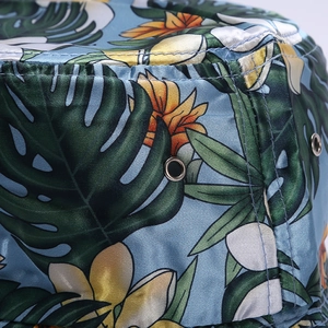 Close-up detail showing the tropical monstera leaf and floral print on satin bucket hat