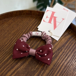 Detail view of pink polka dot scrunchie with a burgundy bow and AE fabric label
