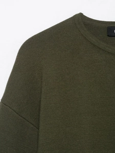 Nahaufnahme der olivgrünen Strickjacke mit Details zu Halsausschnitt und Schulternaht