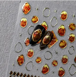 Macro detail of amber texture nail stickers with 3D gold foil edges and metallic charms