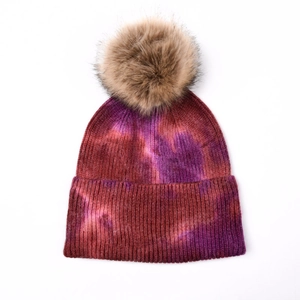 Vue détaillée du bonnet en tricot tie-dye avec un pompon duveteux en fausse fourrure