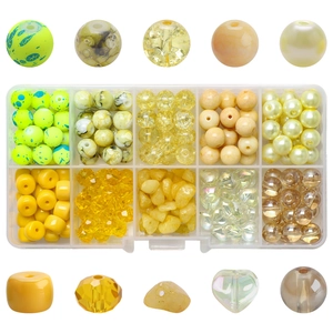 Detailed view of yellow crystal beads and glass charms in a 10-grid storage box for DIY jewelry