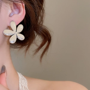 Gros plan d'un mannequin portant des boucles d'oreilles fleurs argentées au design noeud