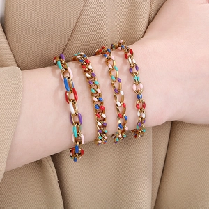 Women's 18K gold plated Cuban link bracelets with colorful enamel inlay on a beige suit