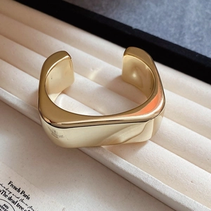 Detailed view of a golden minimalist square-round open bangle on a velvet jewelry tray