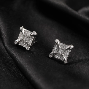 Macro shot of square zircon earrings with claw design on black silk background