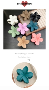 Detailed close-up of matte flower hair claws in multiple colors on a wooden display tray