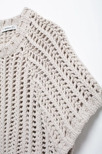 Détail de l'encolure d'un pull en maille épaisse beige montrant la texture au crochet