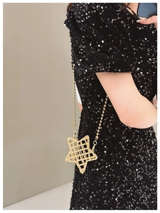 Detail of star-shaped gold metal crossbody bag with beaded chain on a model