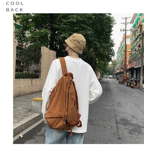 Brown canvas backpack for students shown in a lifestyle street view on a model