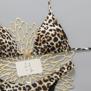 Detail of leopard print bikini top with decorative gold sun-shaped metal clasp