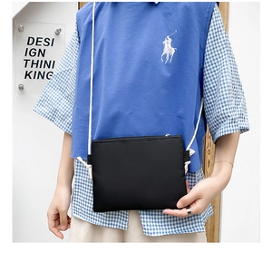 Detail of a minimalist black canvas crossbody bag with white rope straps worn by a model