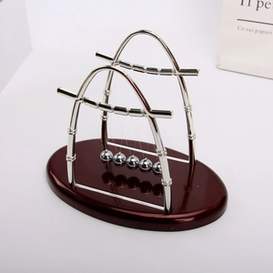 Detail of Newton's cradle with silver metal balls and red glossy wooden base decor