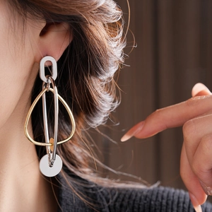Détail macro de boucles d'oreilles géométriques oversize en métal bicolore