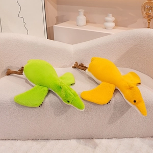 Soft cartoon pterodactyl plush toy in green and yellow colors on a cozy sofa