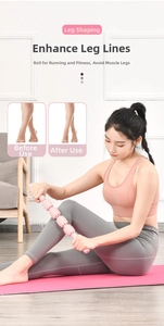 Pink handheld muscle massage roller stick for leg relaxation on a yoga mat