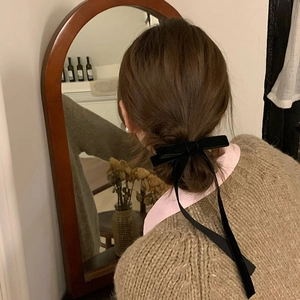 Elegant velvet bow hair clip with long ribbons worn on a low bun hair style