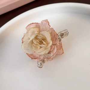 Close-up of gradient pink camellia flower hair claw with scorched edges fabric detail