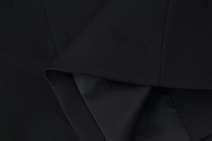 Macro shot of black V-neck jacket fabric showing textured exterior and smooth inner lining
