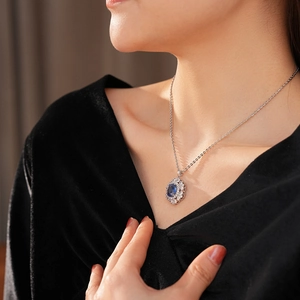 Primo piano di una collana vintage con una grande gemma blu ovale indossata da una modella