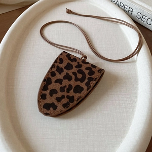 Detail of leopard print leather dog-shaped pendant with matching lanyard on a tray