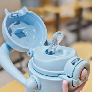 Close-up of light blue kids water bottle lid with transparent silicone straw and handle