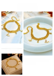 Detail of gold double-layer chain bracelet with butterfly charm and zircon pendant