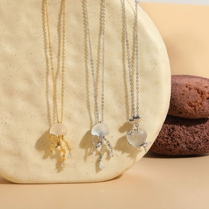 Artistic display of jellyfish and heart pendants on stone with gold and silver finishes