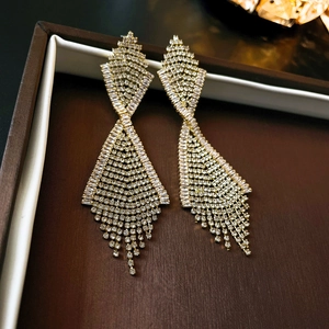 Macro detail of gold tassel earrings with sparkling cubic zirconia on a jewelry box